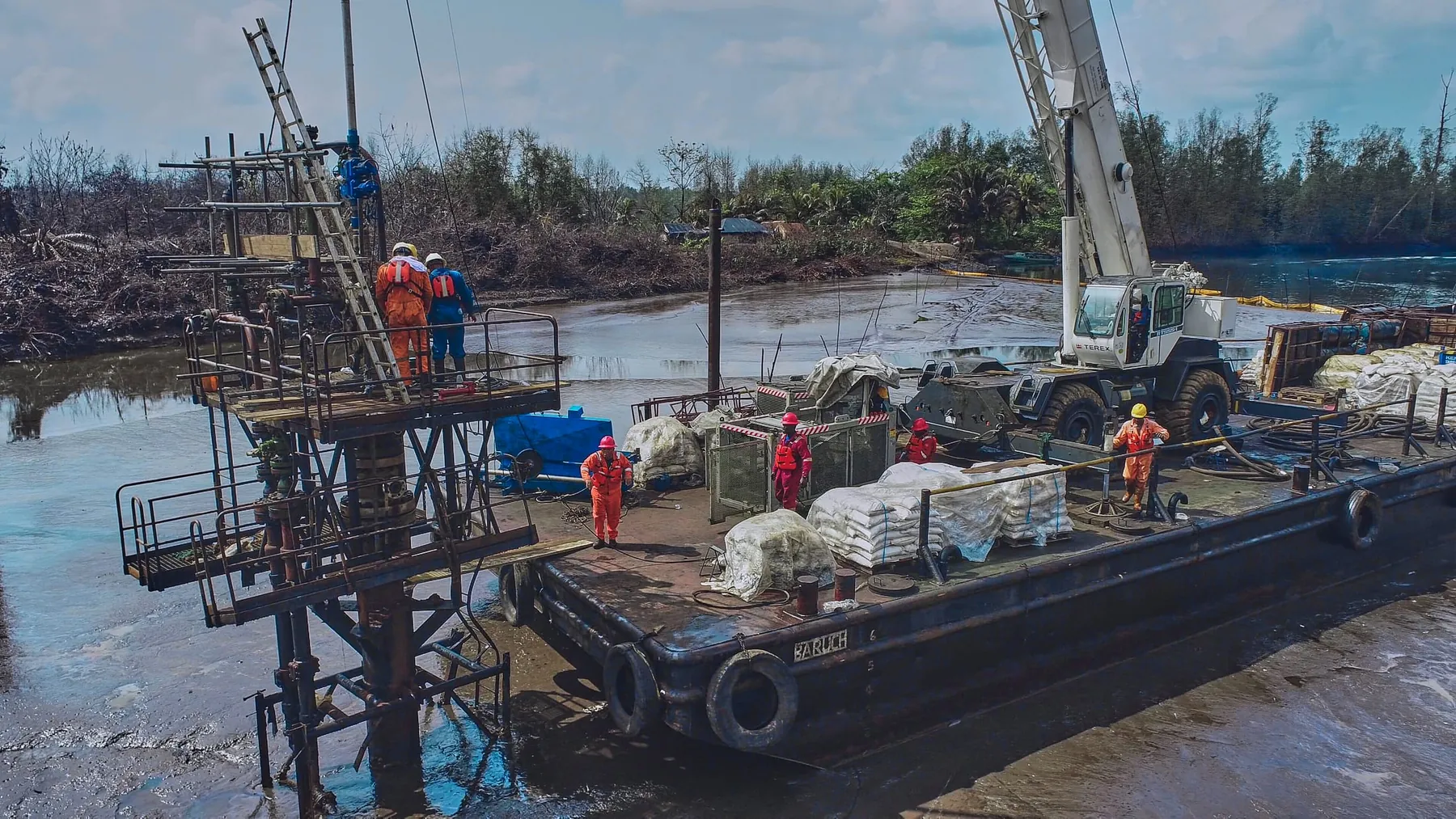 Barge-mounted crane and crew at a swamp wellhead