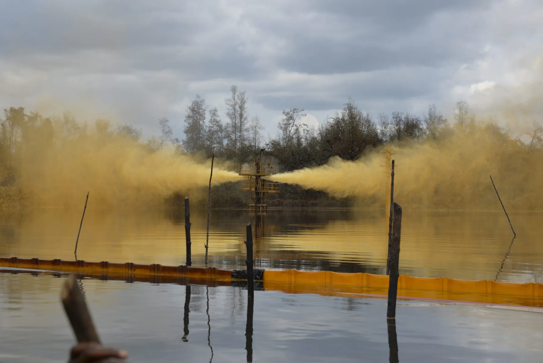 Swamp wellhead venting across the water, containment boom deployed